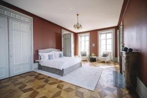 a bedroom with a white bed and some windows at Le Château de l'Aile in Vevey
