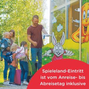 einem Mann mit einer Gruppe von Kindern vor einem Spielplatz in der Unterkunft Ravensburger Spieleland Feriendorf in Meckenbeuren