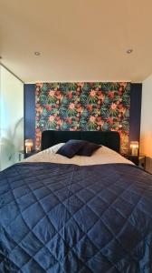 a bedroom with a blue bed with a floral wall at Maui - zeezichtappartement te Oostende in Ostend