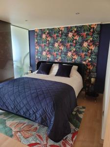 - une chambre avec un grand lit et un mur fleuri dans l'établissement Maui - zeezichtappartement te Oostende, à Ostende