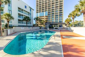 a swimming pool in front of a building with palm trees at Oceanfront 1 bedroom King suite- Ocean Forest Plaza 1911 in Myrtle Beach