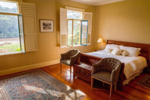 a bedroom with a bed and two chairs and a window at Tizzana Winery Bed and Breakfast in Sackville Reach