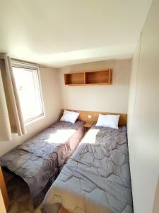 two beds in a small room with a window at Mobil-Home Eucalyptus Valras-Plage in Valras-Plage