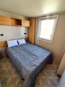 a bedroom with a large bed with a window at Mobil-Home Eucalyptus Valras-Plage in Valras-Plage