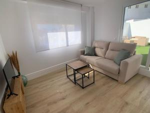 ein Wohnzimmer mit einem Sofa und einem Tisch in der Unterkunft Ático Mármoles - Centro Málaga in Málaga