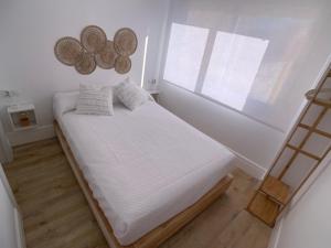 Schlafzimmer mit einem Bett mit weißer Bettwäsche und einem Fenster in der Unterkunft Ático Mármoles - Centro Málaga in Málaga