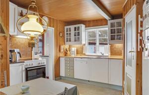 cocina con armarios blancos, mesa y lámpara de araña en 3 Bedroom Awesome Home In Bog By en Bogø By