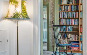 um quarto com uma cadeira e uma estante de livros com livros em 3 Bedroom Awesome Home In Bog By em Bogø By