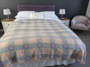 a bed with a colorful blanket and a chair at Samuel cottage in Caernarfon