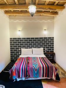 1 dormitorio con 1 cama colorida y pared de ladrillo en Hiking Nomads Guesthouse en Tamellalt