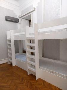 two white bunk beds in a room with wooden floors at A & F HOSTEL in Baku