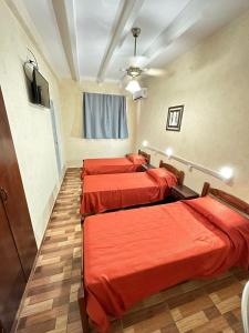 three beds in a room with red sheets at Centro1555 in Buenos Aires