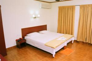 1 dormitorio con 1 cama blanca grande en una habitación en Hotel Srinivas, en Kochi