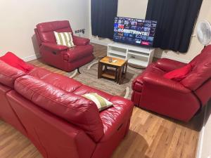 a living room with two red couches and a television at JustAlf Facilities-Spacious 2-bed apartment in Thamesmead, Greenwich in London