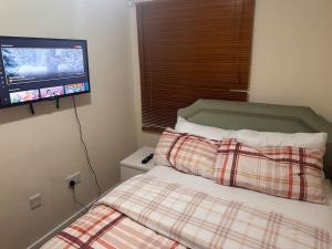 a bedroom with a bed and a tv on the wall at JustAlf Facilities-Spacious 2-bed apartment in Thamesmead, Greenwich in London