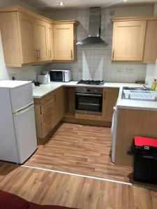 a kitchen with white appliances and wooden cabinets at JustAlf Facilities-Spacious 2-bed apartment in Thamesmead, Greenwich in London