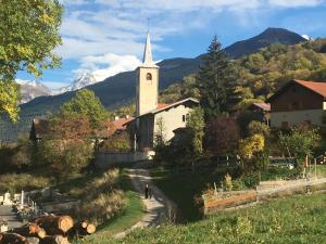 a church with a steeple in a village with mountains at LE BAROQUE in Aime-La Plagne