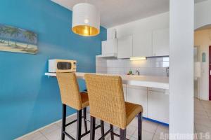 een keuken met 2 stoelen en een aanrecht met een magnetron bij Bonaire Oceanfront Apartments in Kralendijk