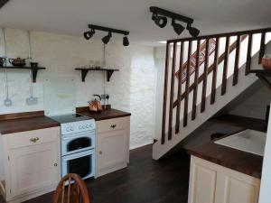 a kitchen with a stove and a staircase at Converted rural stone cottage, Swansea in Swansea