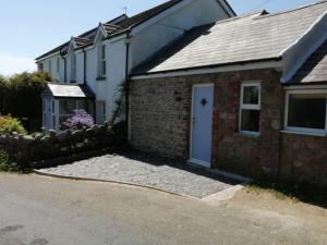 a brick house with a white door and a driveway at Converted rural stone cottage, Swansea in Swansea