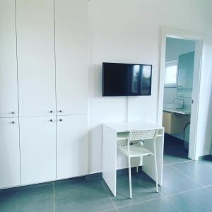 a white room with a desk and a tv on a wall at Villa Verano Apartamentos Compartidos Villaverde in La Oliva