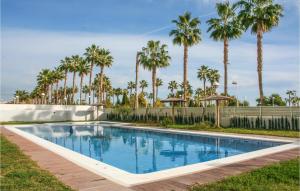 a swimming pool with palm trees in the background at Cozy Apartment In Oropesa Del Mar in Oropesa del Mar