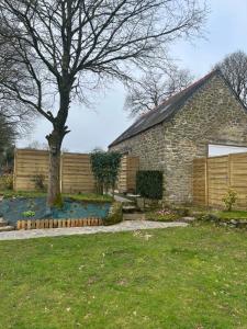 a brick house with a tree in the yard at La petite maison de Kerguiniou in Glomel