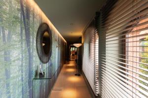 - un couloir d'une maison avec un miroir et une fenêtre dans l'établissement Hostellerie La Cheneaudière & Spa, à Colroy-la-Roche