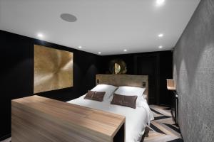 a bedroom with a large white bed and a wooden table at Hostellerie La Cheneaudière & Spa in Colroy-la-Roche