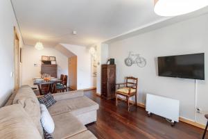 uma sala de estar com um sofá e uma televisão de ecrã plano em D João IV Apartment With Terrace by LovelyStay no Porto