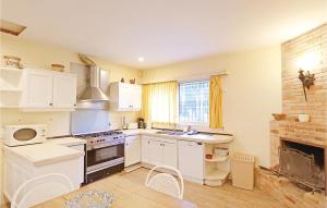 kuchnia z białymi szafkami i kominkiem w obiekcie 10 Bedroom Cozy Home In Vilanova Del Valls w mieście Vallromanas
