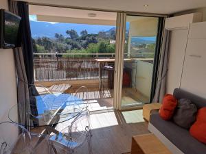 ein Wohnzimmer mit einem Glastisch und einem Balkon in der Unterkunft Farfalla in Calvi