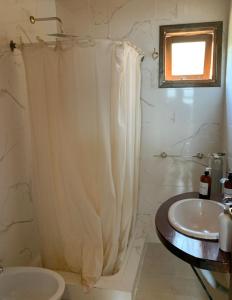 y baño con cortina de ducha y lavamanos. en Hosteria Hainen en El Calafate