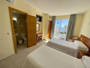 a hotel room with two beds and a balcony at Hotel Cabello in Torremolinos