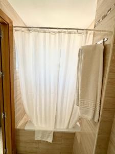 a shower with a white shower curtain and a towel at Hotel Cabello in Torremolinos