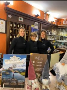 un grupo de tres mujeres de pie en una tienda en Hotel Ristorante Ligure en Vinadio