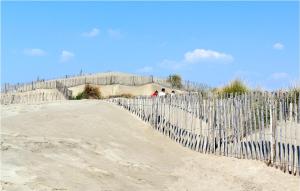 エーグ・モルトにある2 Bedroom Amazing Home In Aigues-Mortesの砂浜の柵と砂の上を歩く人々