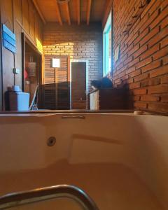 a bathroom with a sink and a brick wall at Chalé Sol com hidromassagem em meio a natureza in Piçarras +34 photos