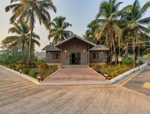 a house with palm trees in front of it at Hotel Aaradhya Adorer in Kudal