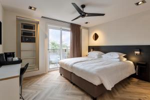 a bedroom with a large bed with a ceiling fan at Hotel Hogerhuys - adults only in Noordwijk aan Zee