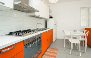 a kitchen with orange and white cabinets and a table at Beautiful Apartment In Magliolo With Outdoor Swimming Pool, Sauna And 1 Bedrooms in Magliolo