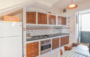 eine Küche mit Holzschränken und einem weißen Kühlschrank in der Unterkunft Cozy Home In Sampieri With House A Panoramic View in Sampieri
