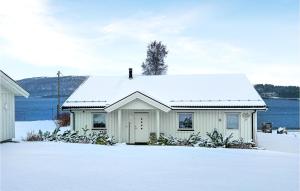 a white house with snow on top of it at Cozy Home In Valsyfjord With House Sea View in Valsøyfjord