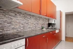 a kitchen with red cabinets and a brick wall at Comfortable 3BR shared Apart. - Suitable For Long Stays in Vienna