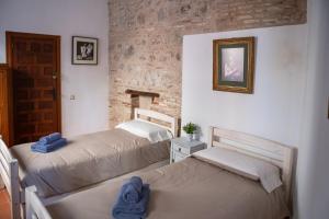 a bedroom with two beds and a brick wall at Hammam de Zeid in Toledo
