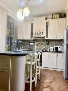 a kitchen with white cabinets and a black counter top at Beauty in the Heart of the City in Tbilisi City