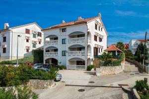 a large white apartment building with a parking lot at Apartments Katarina k in Malinska