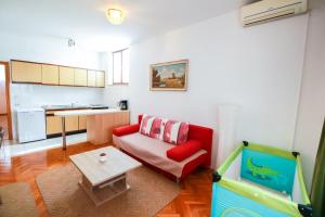 a living room with a red couch and a table at Apartments Katarina k in Malinska