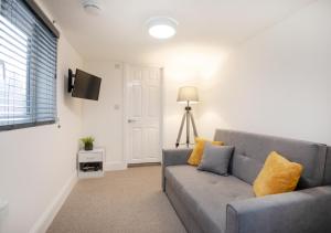 ein Wohnzimmer mit einem grauen Sofa und gelben Kissen in der Unterkunft Fast Wi-FI, Smart TV, Sleeps up to 3, on street parking in Lincolnshire