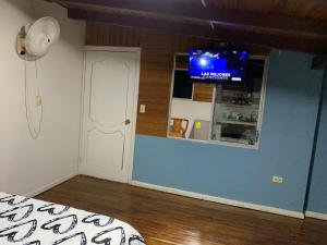 Habitación con puerta blanca y TV en la pared. en MY HOUSE IN MACAS, SUITE AMOBLADA, en Macas